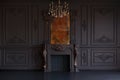 Decorative fireplace, vintage mirror and chandelier in classical black room interior