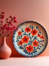 Decorative floral plate with matching vase on pink surface. Royalty Free Stock Photo