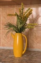 Decorative flowers for home interior in a yellow jug teapot.