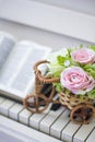 Decorative flowers roses in a wicker bicycle on the piano and the Bible. Topiary. Wedding decor, decoration.