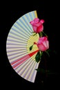 Decorative folding paper fan and a pair of pink roses