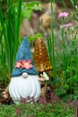 Decorative garden gnome holding a butterfly in flower bed Royalty Free Stock Photo