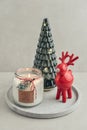 Decorative glass fir tree with red ceramic deer and candle in jar