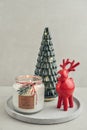 Decorative glass fir tree with red ceramic deer and candle in jar