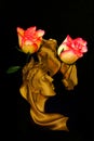 Kissing couple golden sculpture with pink roses on dark background