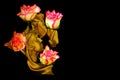 Kissing couple golden sculpture with four pink roses on dark background