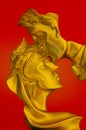 Decorative golden sculpture of kissing couple on red background