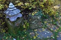 Decorative guard stone with top shaped like japanese miniature pagoda or temple, standing near park pathway