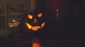 Decorative, Halloween pumpkin statue with lit candle glowing in the dark on the shelf in living room