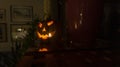 Decorative Halloween pumpkin statue lit with candle glowing in the dark on the shelf in living room