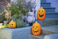 Decorative halloween pumpking or jack o'lanterns with carved faces on blue painted cement stairs and front yard