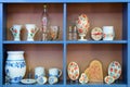 Decorative hand colored bottles glasses cups on the blue shelf