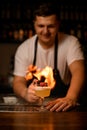 decorative heart on glass with foamy cocktail on the bar and male bartender with fire on background
