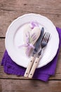 Decorative heart, knife and fork on white plate on vintage wooden background.