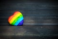 Decorative Heart with rainbow stripes on dark wooden background. LGBT pride flag, symbol of lesbian, gay, bisexual, transgender