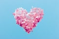 Decorative heart shape made of pink sequins on an isolated blue background.