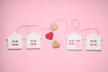 Decorative hearts and cord between white house models on pink background symbolizing connection in long-distance relationship,