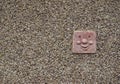A decorative House tile of a caricature of a smiling Person set into a brown hailed wall of a house. Royalty Free Stock Photo