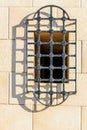 Intricate Iron Window Grille Over Beige Stone Wall Casting Long Shadow in Warm Sunlight Royalty Free Stock Photo