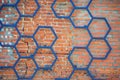 Decorative iron pattern of black metal in the shape of a honeycomb on the background of a red brick wall Royalty Free Stock Photo