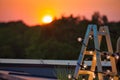 Photo of decorative ladder with lights against sunset at rooftop