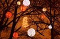 decorative large red, gold and white ornamental christmas lights in public park suspended from bare winter tree branches