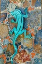 Decorative metal blue lizard on colorful stone wall.