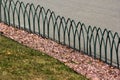 Decorative metal fence and gravel belt between lawn and sidewalk in a park