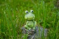 Decorative miniature frog.Small funny Frog statue in the grass in garden. Copy space.Green ceramic Figure of a green