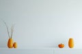 Decorative orange vases with dried branches arranged on a clean, white shelf in a modern interior setting Royalty Free Stock Photo