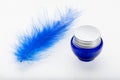 Decorative ostrich feather and blue cosmetic bottle isolated on white background