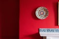 Decorative painting on a plate on a deep red wall in a cozy room