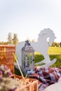 Decorative photozone for 1 year old boy birthday outdoors. Plaid, lantern, basket with dry flowers, rocking horse on green lawn.