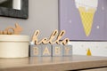 Decorative phrase HELLO BABY on table in baby room. Interior design