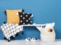Decorative pillows and blanket with pom-poms on a wooden bench,cozy soft slippers and wicker basket