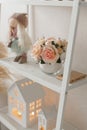 Decorative pink flowers in a round vase on a white shelf. Beautiful decor for the home Royalty Free Stock Photo