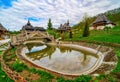 Decorative pond and wooden bridge in Barsana monastery, Romania. Traditional Maramures wooden architecture on background