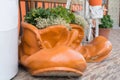 Decorative pot with flowers, made in the form of large boots. Stands in the city center, near the city shop.