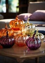 Decorative pumpkins of different sizes and shapes made of colored glass. Stylish Halloween decor. White blurred living