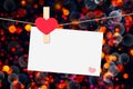 Decorative red heart with blank greeting card hanging on golden light bokeh background with space for text