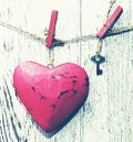 Decorative red heart and small metal key on a rope against the background of an old white board Royalty Free Stock Photo