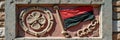 Decorative relief with red-black flag and ornate symbols on stone wall Royalty Free Stock Photo