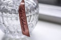 Decorative retro glass jar container with a pattern with a pink ribbon with text Lets Celebrate on a white windowsill