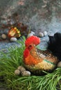 Decorative rooster, rooster with sequins on fresh green grass and with folk red cloth, black feathers in the rooster`s tail