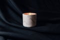 Decorative scented candle burns against black fabric