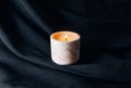 Decorative scented candle burns against black fabric