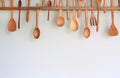 Decorative set of wooden kitchen utensils hanging on white wall background Royalty Free Stock Photo