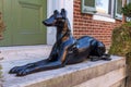 A decorative shiny black dog model put in front of the entrance of a historic brick building in old town