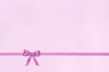 Decorative shiny ribbon with bow on pink background.