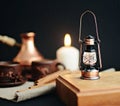 Decorative small lantern on a wooden stand, cinnamon sticks, caps of coffee, candle, canvas napkin on a dark background